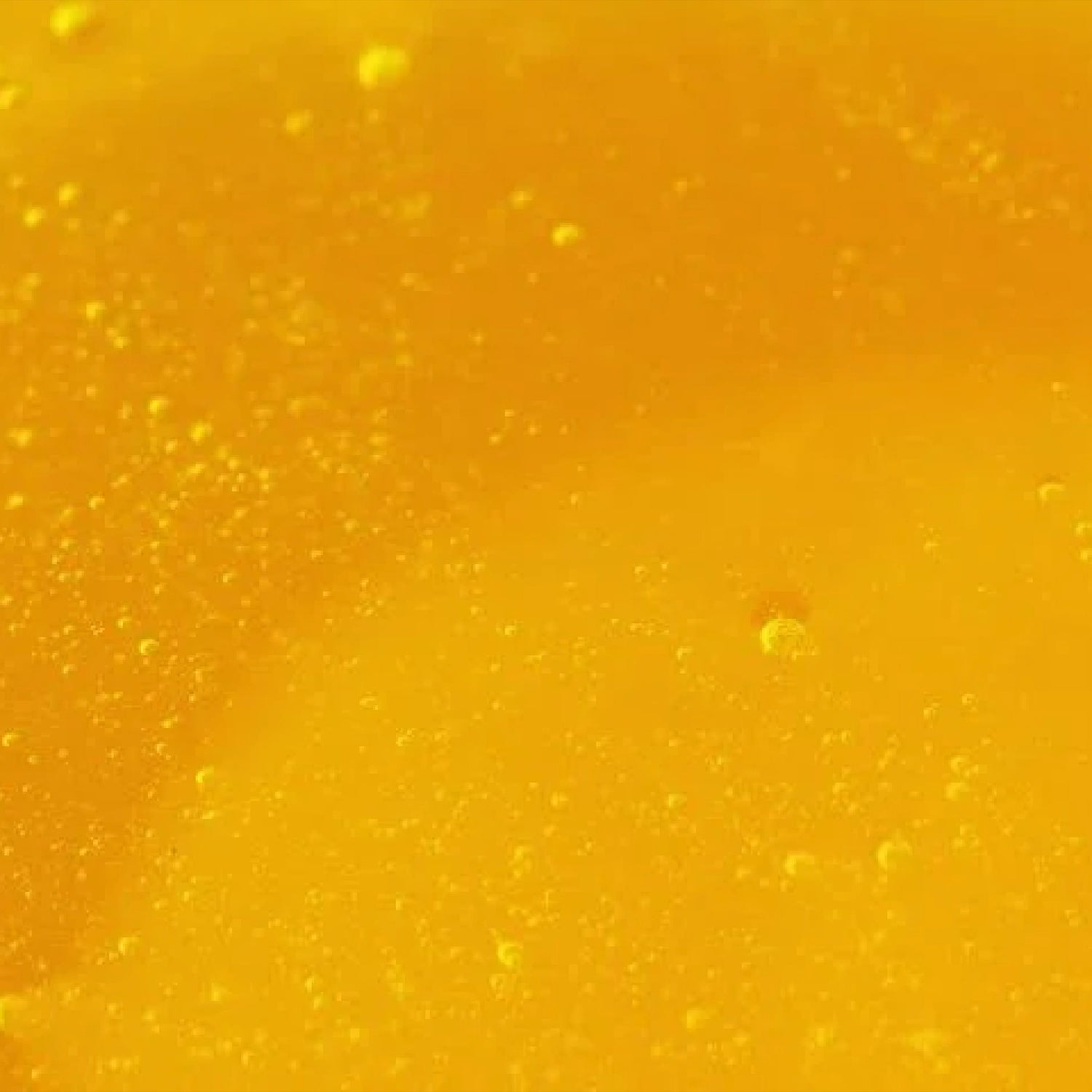 Close-up of a textured yellow surface, apple cider vinegar, with small bubbles scattered throughout. The image has a smooth and glossy appearance, with varying shades of yellow creating depth.